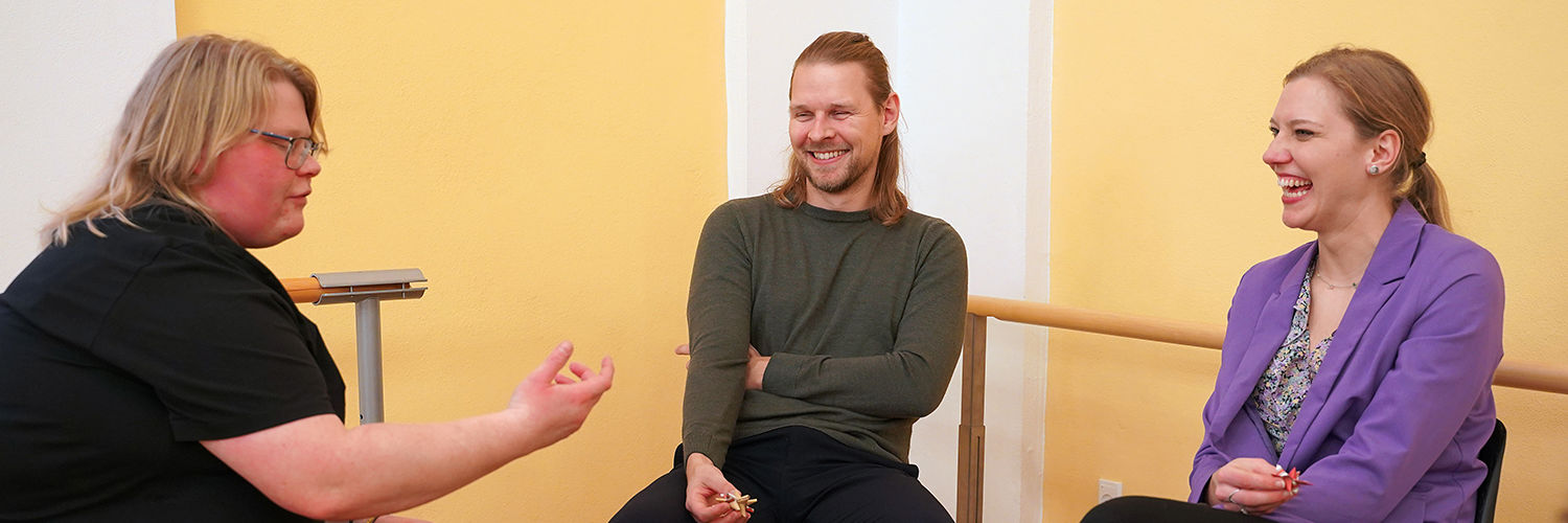 Tre unge mennesker sidder og taler sammen